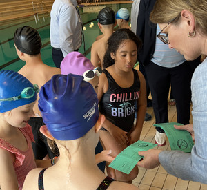 Zu sehen ist Bildungsministerin Dr. Stefanie Hubig, die die ersten Schwimmabzeichen an die Schülerinnen und Schüler der Grundschule am Mühlbach in Saulheim übergibt.