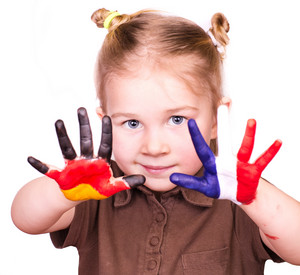Mädchen das eine Handinnenfläche mit der deutschen und die andere Handinnenfläche mit der französischen Flagge bemalt hat.
