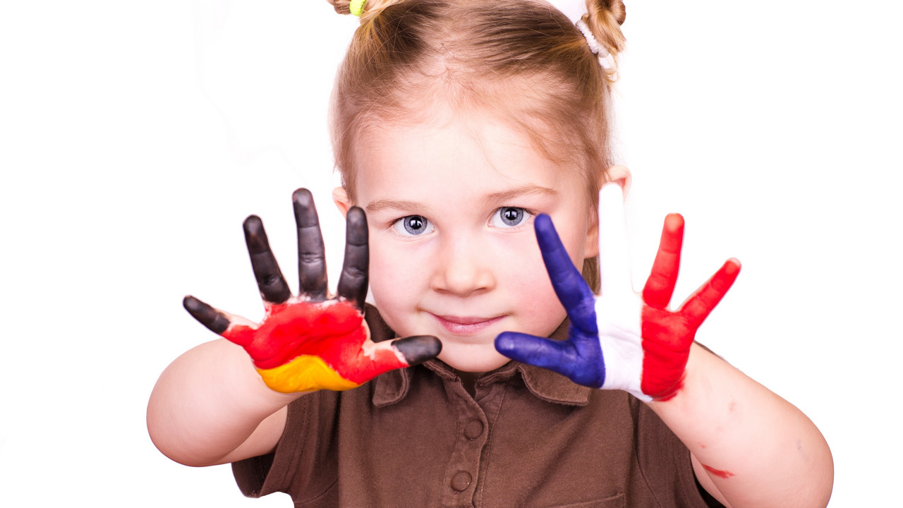 Mädchen das eine Handinnenfläche mit der deutschen und die andere Handinnenfläche mit der französischen Flagge bemalt hat.