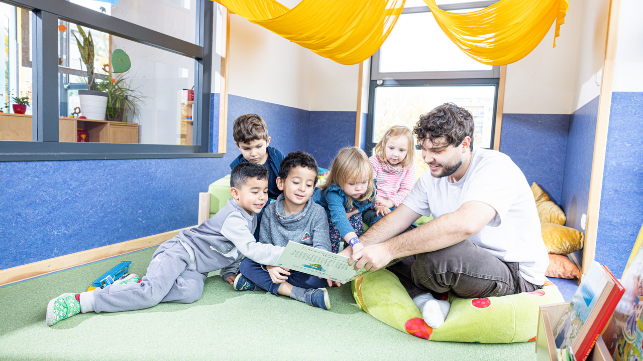 Erzieher liest Kindern ein Buch vor.