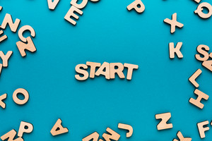 Holzbuchstabend auf blauem Untergrund die das Wort Start formen