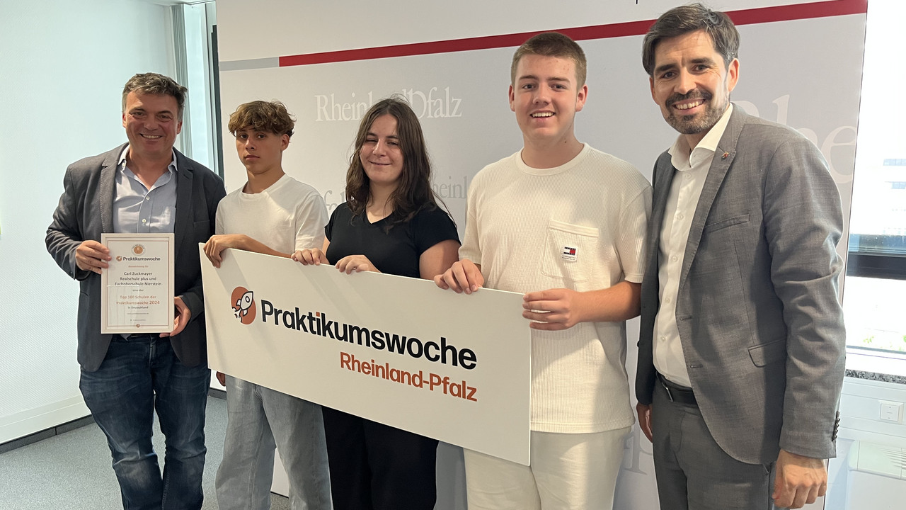 Bildungsminister Sven Teuber (rechts) überreicht die Urkunde zur Praktikumswoche an die Carl-Zuckmayer Realschule plus mit Fachoberschule Nierstein.