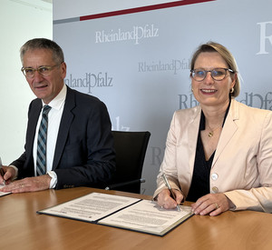 Zu sehen sind Der Vorsitzende des Volkshochschulverbandes Rheinland-Pfalz, Landtagspräsident Hendrik Hering und Bildungsministerin Dr. Stefanie Hubig während der Unterzeichnung. 