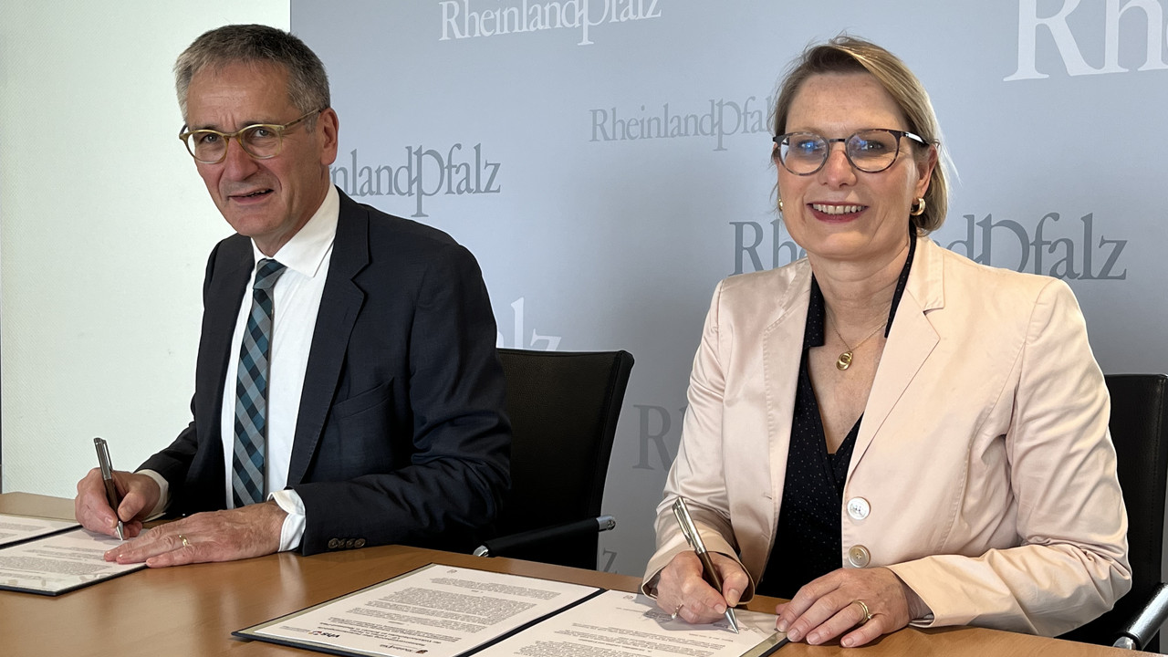 Zu sehen sind Der Vorsitzende des Volkshochschulverbandes Rheinland-Pfalz, Landtagspräsident Hendrik Hering und Bildungsministerin Dr. Stefanie Hubig während der Unterzeichnung. 