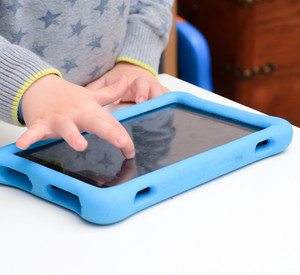 Kleinkind tippt mit den Fingern auf dem Bildschirm eines Tablets.