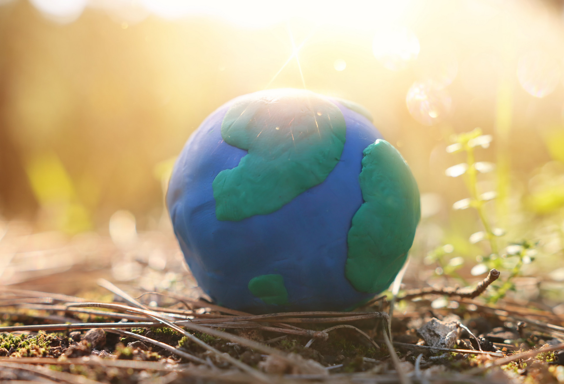 Modell der Erde aus Knete liegt auf dem Boden im Freien.