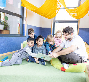 Pädagogische Fachkraft liest gemeinsam mit Kindern ein Buch.