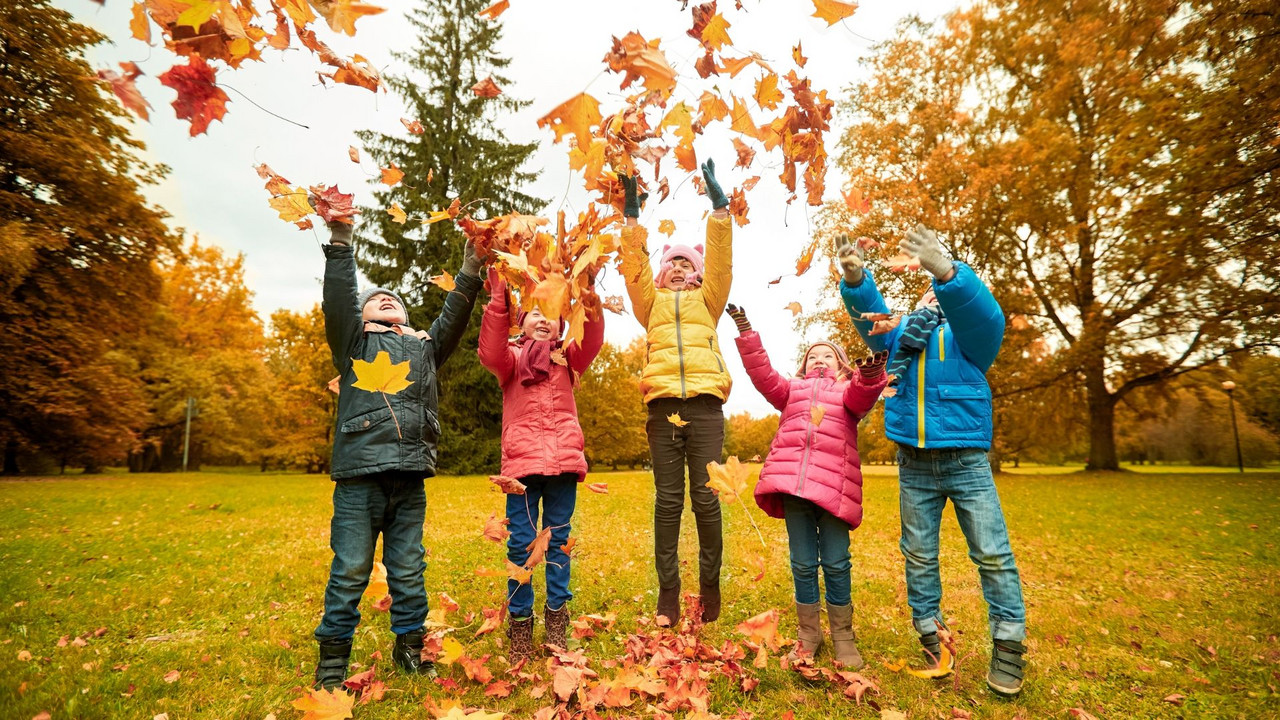Kinder spielen mit buntem Herbstlaub