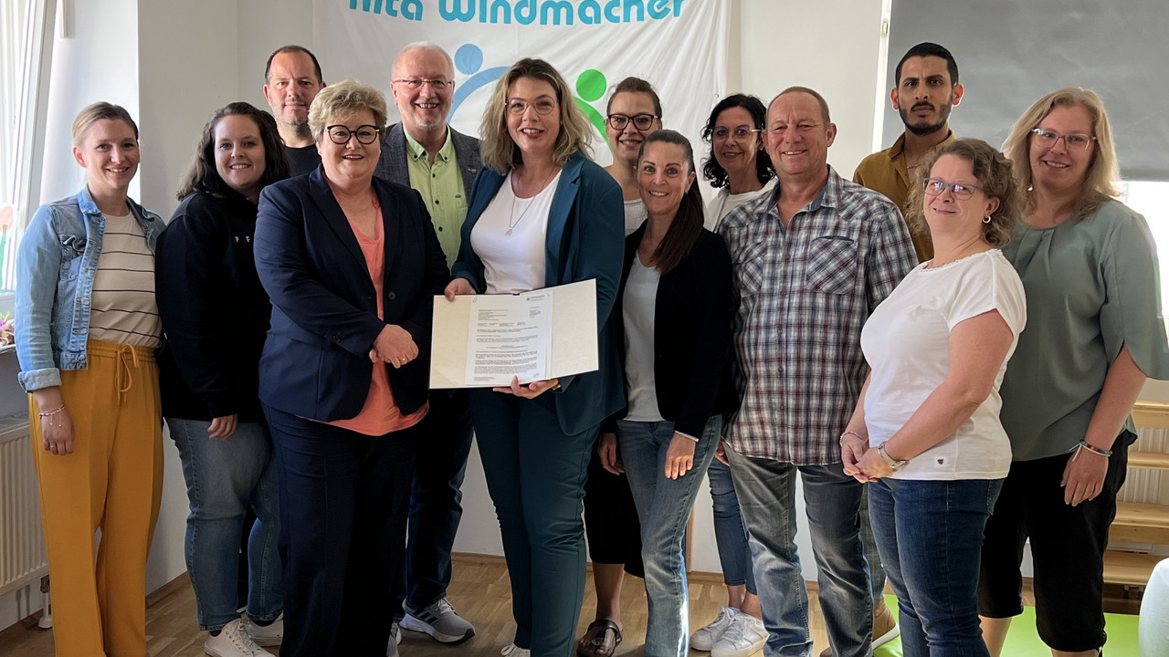 Ein Gruppenbild während der Bescheidübergabe. Zusehen sind Staatssekretärin Brück und die Mitarbeiterinnen und Mitarbeiter der Kita. 